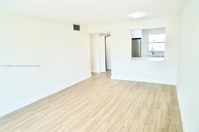unfurnished living room with light wood-style floors, baseboards, and visible vents