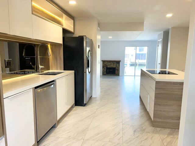 3811 NE 166th St Unit 3, North Miami Beach, FL 33160 - kitchen featuring a stone fireplace, modern cabinets, light countertops, white cabinets, and stainless steel appliances