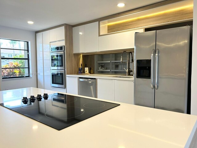 3811 NE 166th St Unit 3, North Miami Beach, FL 33160 - kitchen with appliances with stainless steel finishes, a sink, light countertops, white cabinetry, and modern cabinets