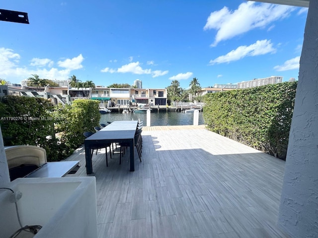 deck featuring a water view, outdoor dining area, and a boat dock