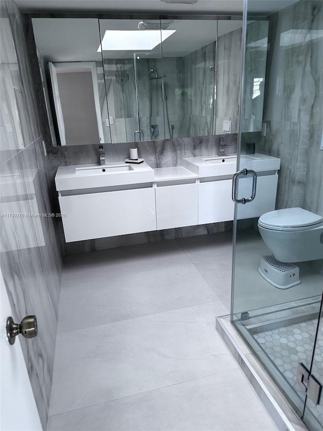 full bathroom featuring double vanity, a sink, a stall shower, and toilet