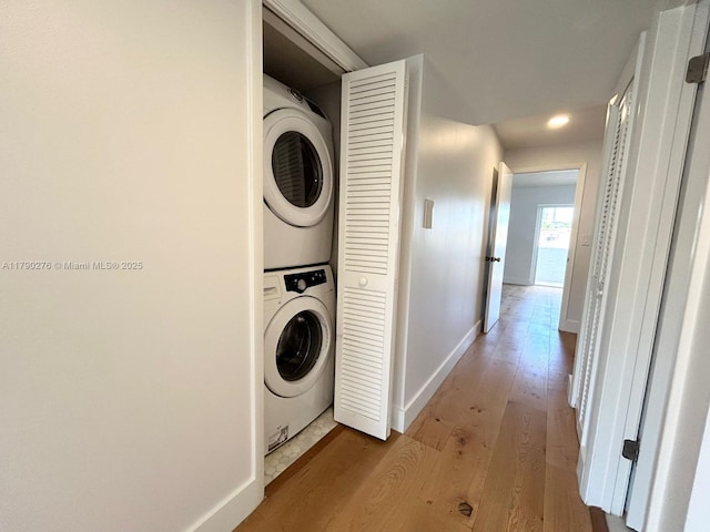 laundry room with laundry area, stacked washer and clothes dryer, baseboards, recessed lighting, and light wood-style flooring