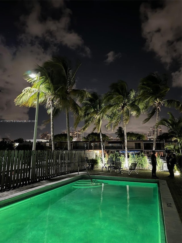 pool at twilight featuring a community pool and fence
