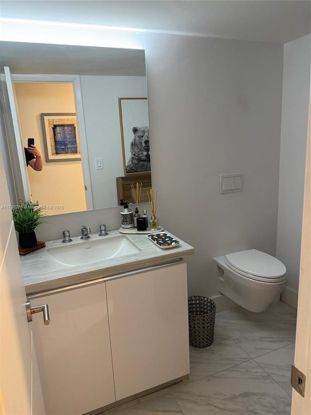 half bathroom featuring vanity, toilet, and marble finish floor