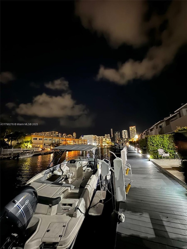 view of dock with a water view and a view of city lights