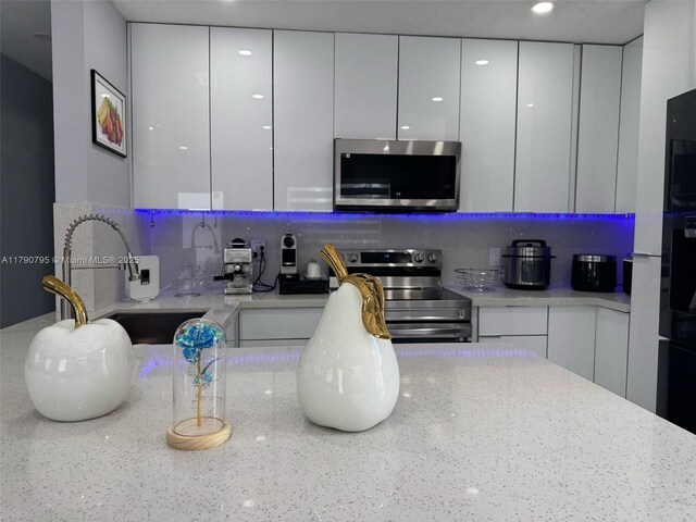 729 E 23rd St, Hialeah, FL 33013 - kitchen featuring modern cabinets, white cabinetry, tasteful backsplash, a sink, and stainless steel appliances