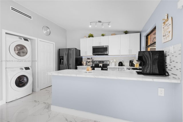 14712 SW 84th Ter, Miami, FL 33193 - kitchen with appliances with stainless steel finishes, stacked washer / dryer, a peninsula, light marble finish floors, and decorative backsplash