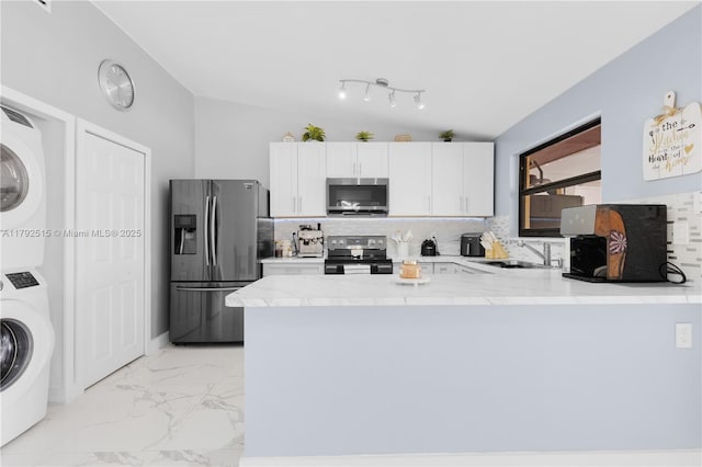 14712 SW 84th Ter, Miami, FL 33193 - kitchen featuring appliances with stainless steel finishes, estacked washer and dryer, vaulted ceiling, a peninsula, and tasteful backsplash