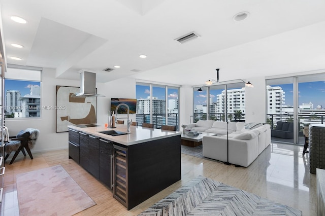 kitchen featuring open floor plan, a city view, range hood, dark cabinetry, and a sink