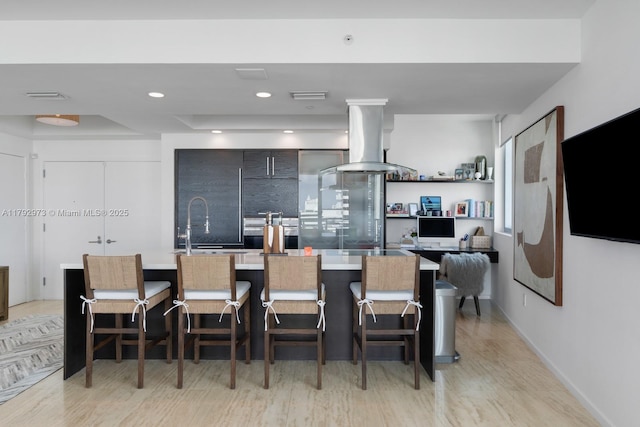 kitchen featuring light wood finished floors, island exhaust hood, visible vents, a center island with sink, and modern cabinets