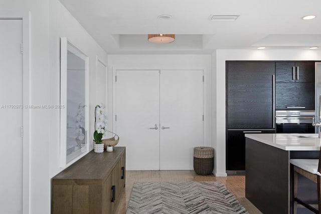 kitchen featuring recessed lighting, visible vents, a raised ceiling, and light wood-type flooring