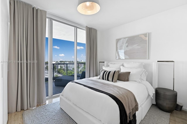 bedroom featuring floor to ceiling windows, light wood finished floors, and access to exterior