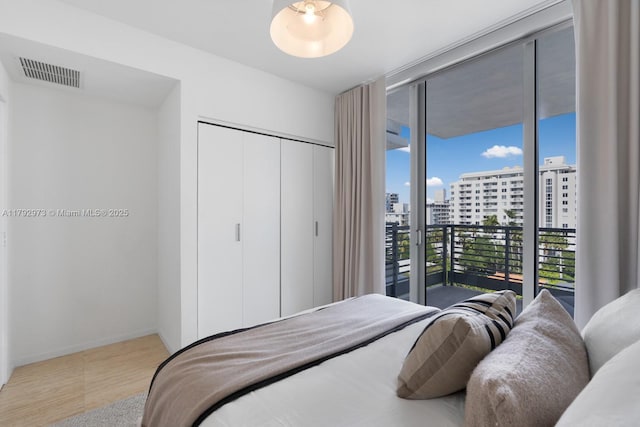 bedroom with visible vents, a view of city, a closet, baseboards, and access to outside