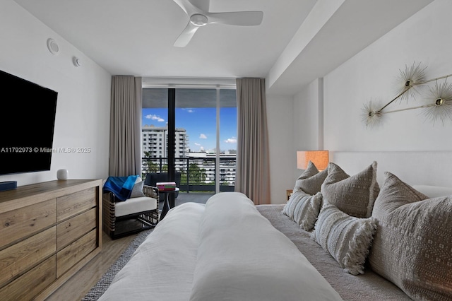 bedroom with floor to ceiling windows, ceiling fan, wood finished floors, and access to exterior