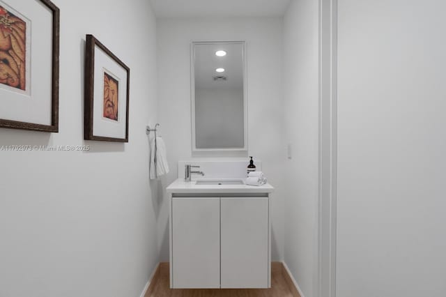 bathroom featuring vanity, recessed lighting, baseboards, wood finished floors, and visible vents