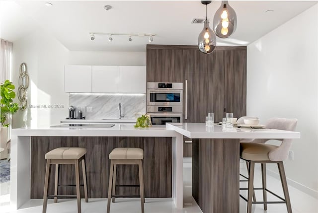 851 NE 1st Ave Unit 2604, Miami, FL 33132 - kitchen featuring stainless steel double oven, modern cabinets, light countertops, white cabinets, and a kitchen bar