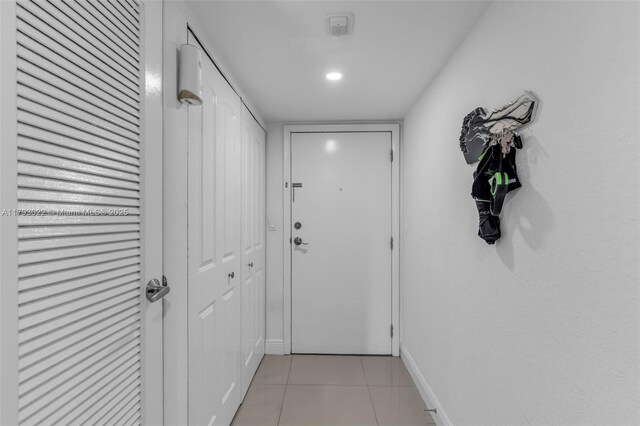 corridor featuring light tile patterned flooring and baseboards