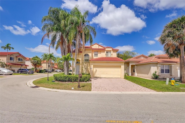mediterranean / spanish-style house with decorative driveway, stucco siding, a tiled roof, an attached garage, and a residential view