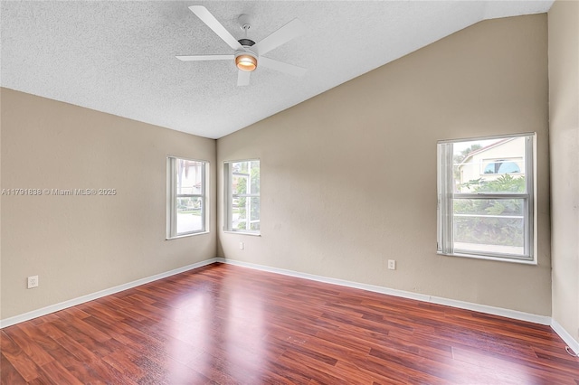 empty room featuring a textured ceiling, a ceiling fan, baseboards, wood finished floors, and vaulted ceiling