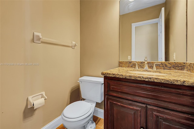 half bathroom featuring toilet, baseboards, and vanity