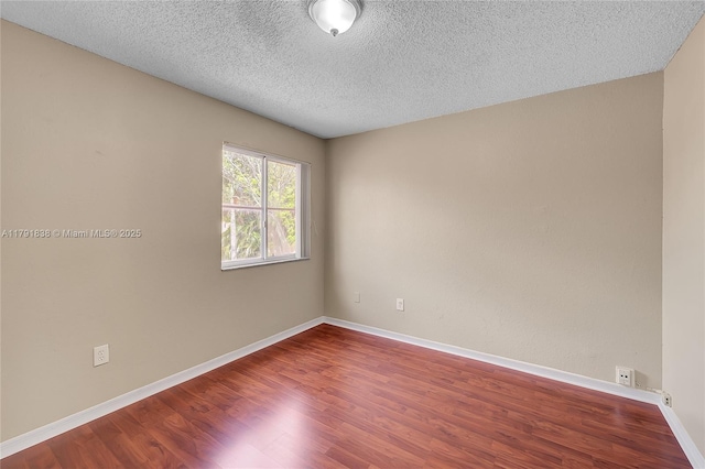 spare room with baseboards, a textured ceiling, and wood finished floors