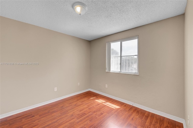 empty room featuring baseboards, a textured ceiling, and wood finished floors