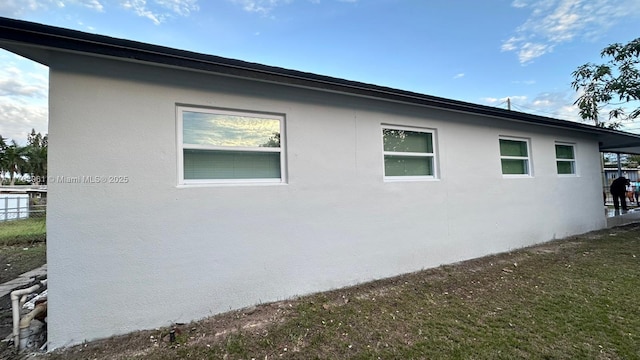 view of side of property with fence and stucco siding