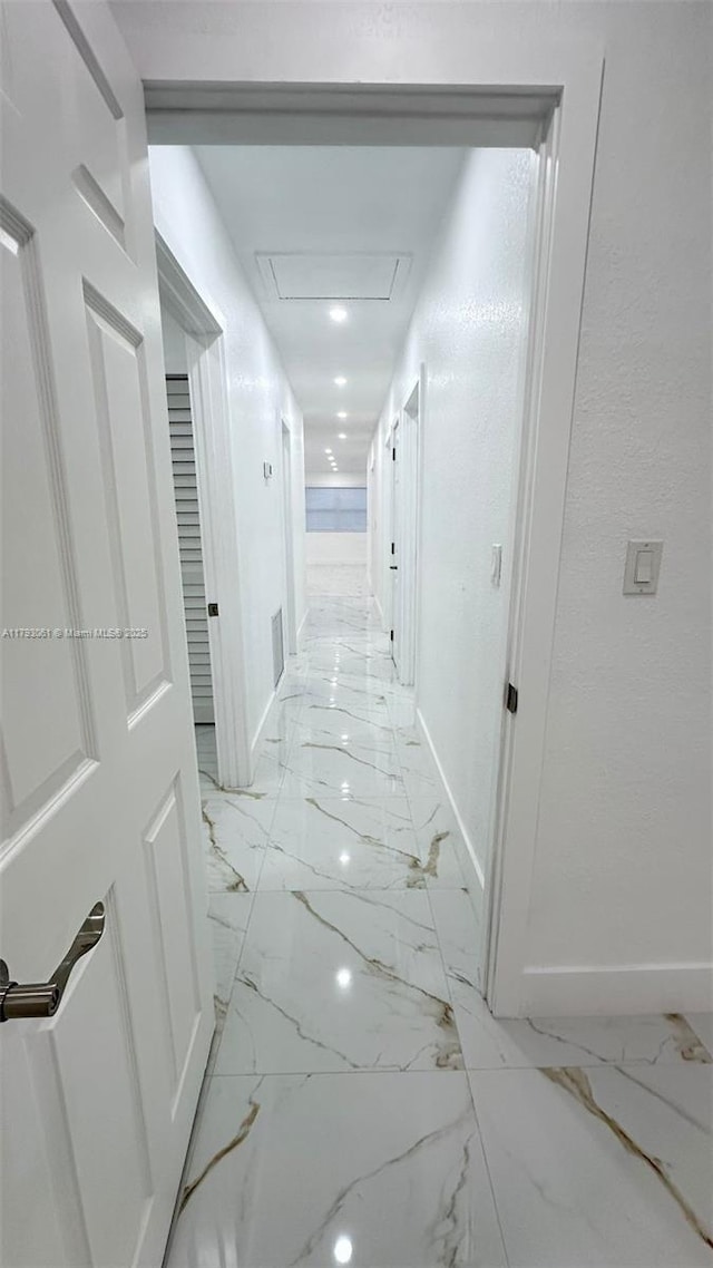 corridor with baseboards, attic access, and marble finish floor