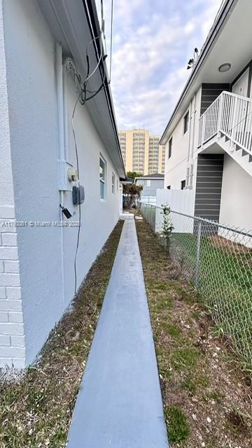 view of side of home featuring fence and stucco siding