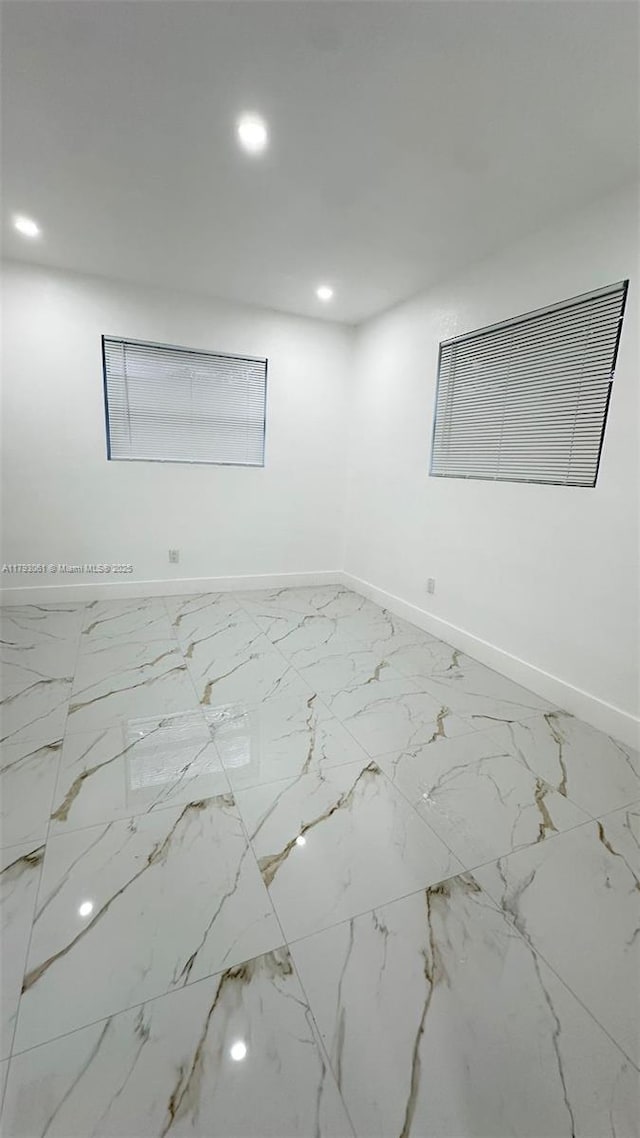 unfurnished room featuring baseboards, recessed lighting, and marble finish floor