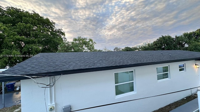 view of side of home with roof with shingles
