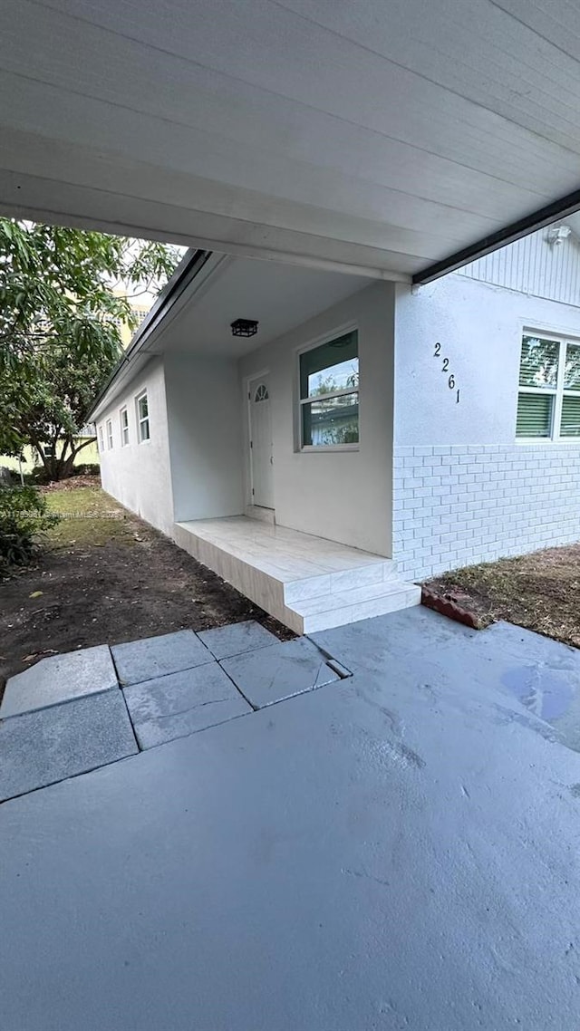 entrance to property featuring brick siding and stucco siding