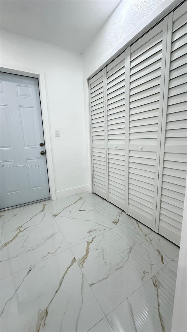 interior space with baseboards and marble finish floor