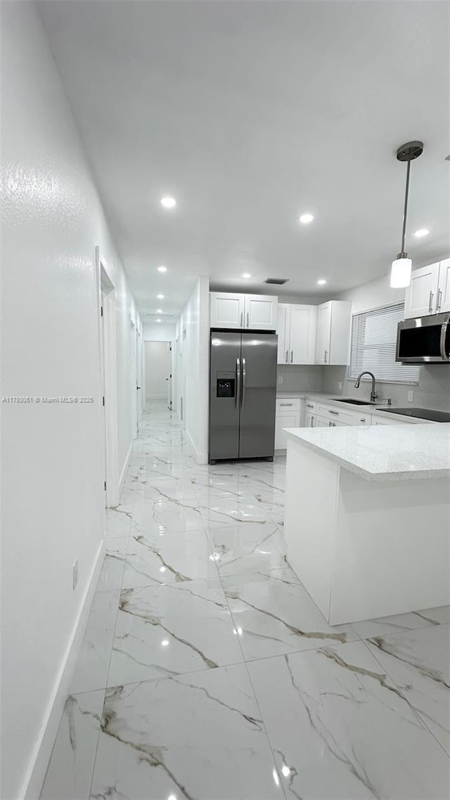 kitchen featuring appliances with stainless steel finishes, a sink, baseboards, white cabinets, and recessed lighting