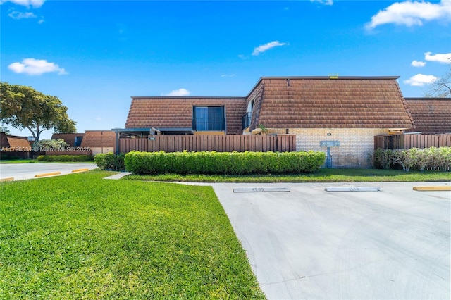 720 7th Ln, Green Acres, FL 33463 - exterior space with uncovered parking, fence, a front yard, mansard roof, and brick siding