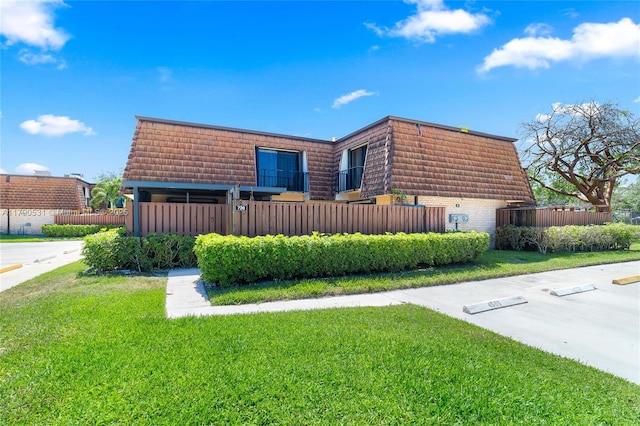 720 7th Ln, Green Acres, FL 33463 - view of front of home featuring fence, mansard roof, a front lawn, and brick siding