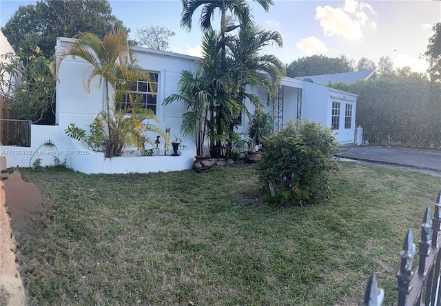 view of side of property featuring a yard, fence, and stucco siding