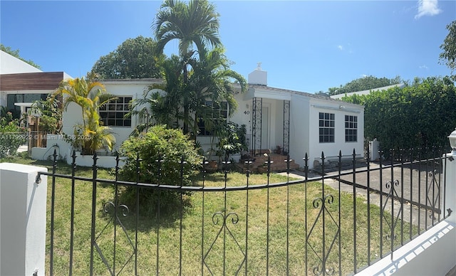 view of front of home with a front lawn, a fenced front yard, stucco siding, and a chimney