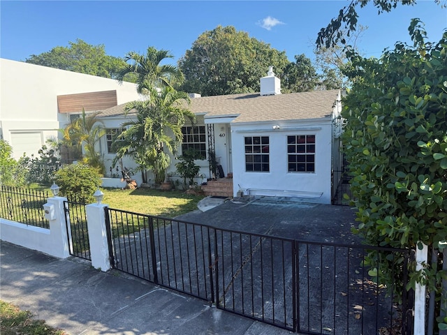 view of front of house featuring a shingled roof, a fenced front yard, stucco siding, a front yard, and a chimney