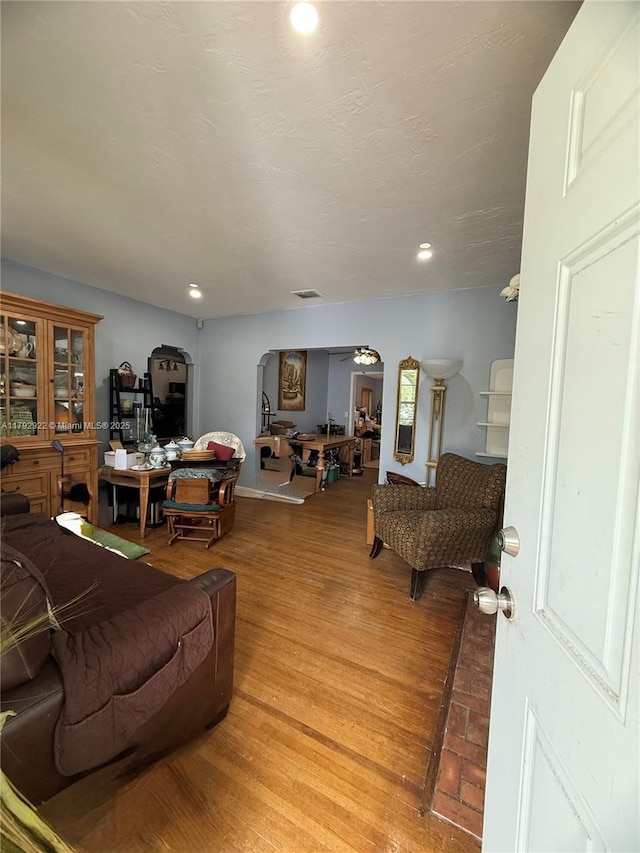 living area with ceiling fan, visible vents, arched walkways, recessed lighting, and light wood-style flooring