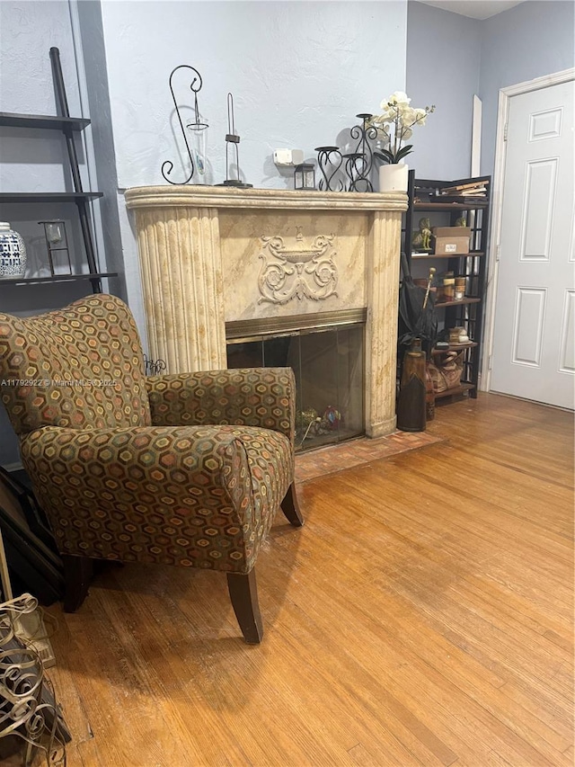 sitting room featuring a high end fireplace and wood finished floors