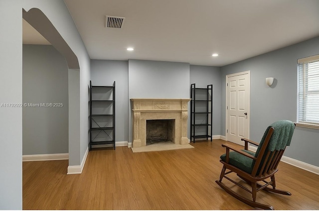sitting room with a premium fireplace, baseboards, visible vents, and wood finished floors