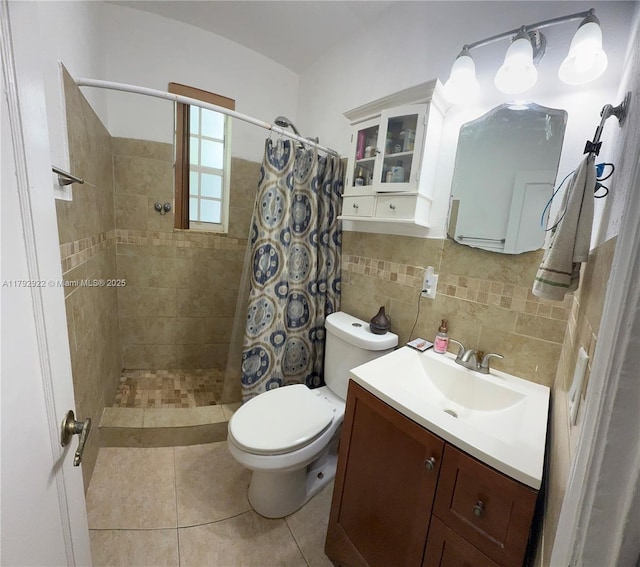 bathroom with a tile shower, tile patterned flooring, vanity, toilet, and tile walls