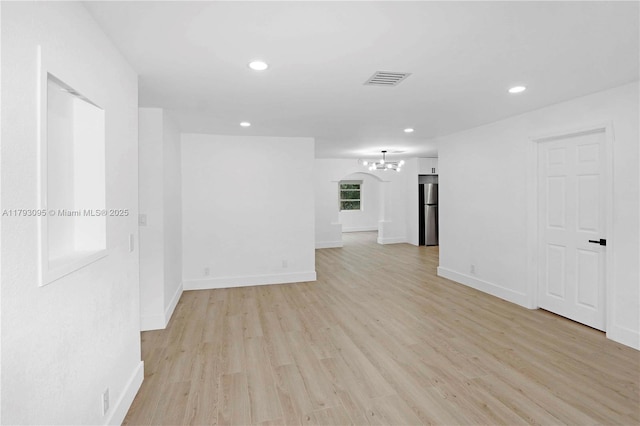 empty room with baseboards, light wood-type flooring, recessed lighting, and a notable chandelier