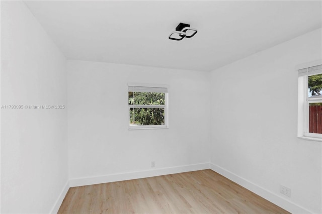 spare room featuring baseboards and light wood-style floors