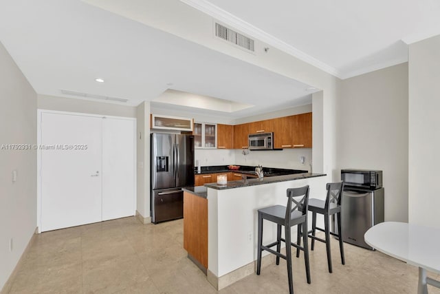 kitchen with visible vents, crown molding, appliances with stainless steel finishes, brown cabinets, and a peninsula