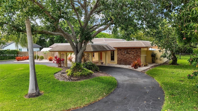 ranch-style home with fence, stucco siding, a front lawn, and aphalt driveway