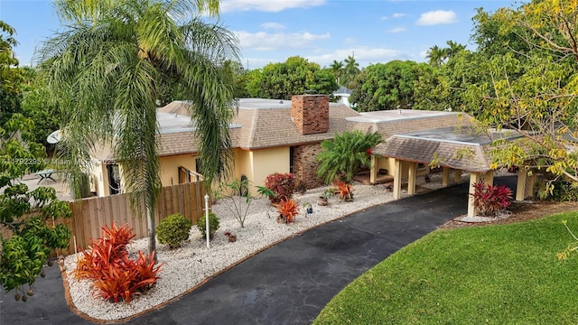 view of front facade with driveway, a chimney, fence, a shingled roof, and stucco siding