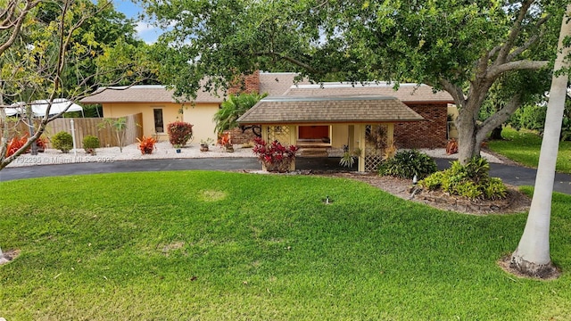 ranch-style home featuring fence, a porch, driveway, and a front yard