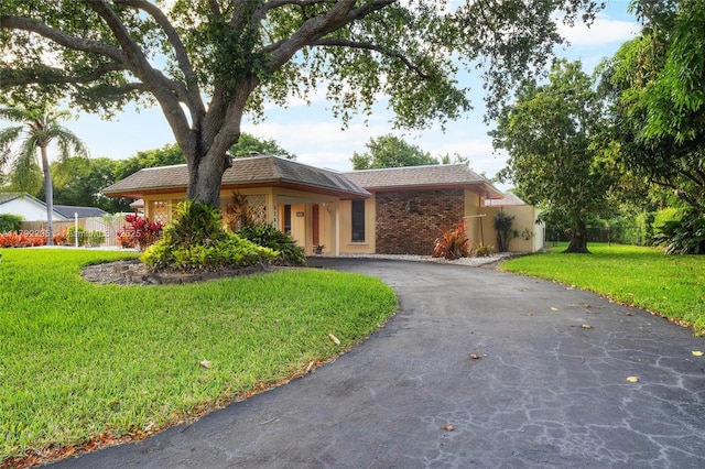 ranch-style house with fence, aphalt driveway, and a front lawn